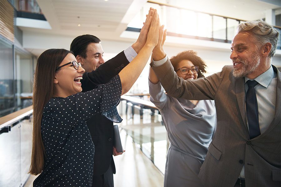 About KBP - Group of Cheerful Employees Celebrating Success By Giving Each Other High Fives